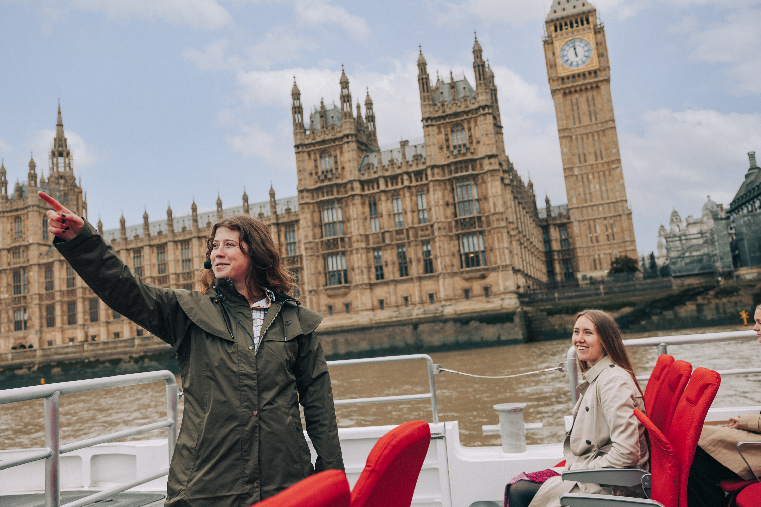 Tour guide pointing and sharing stories of Westminster aboard the Tower of London River Tour