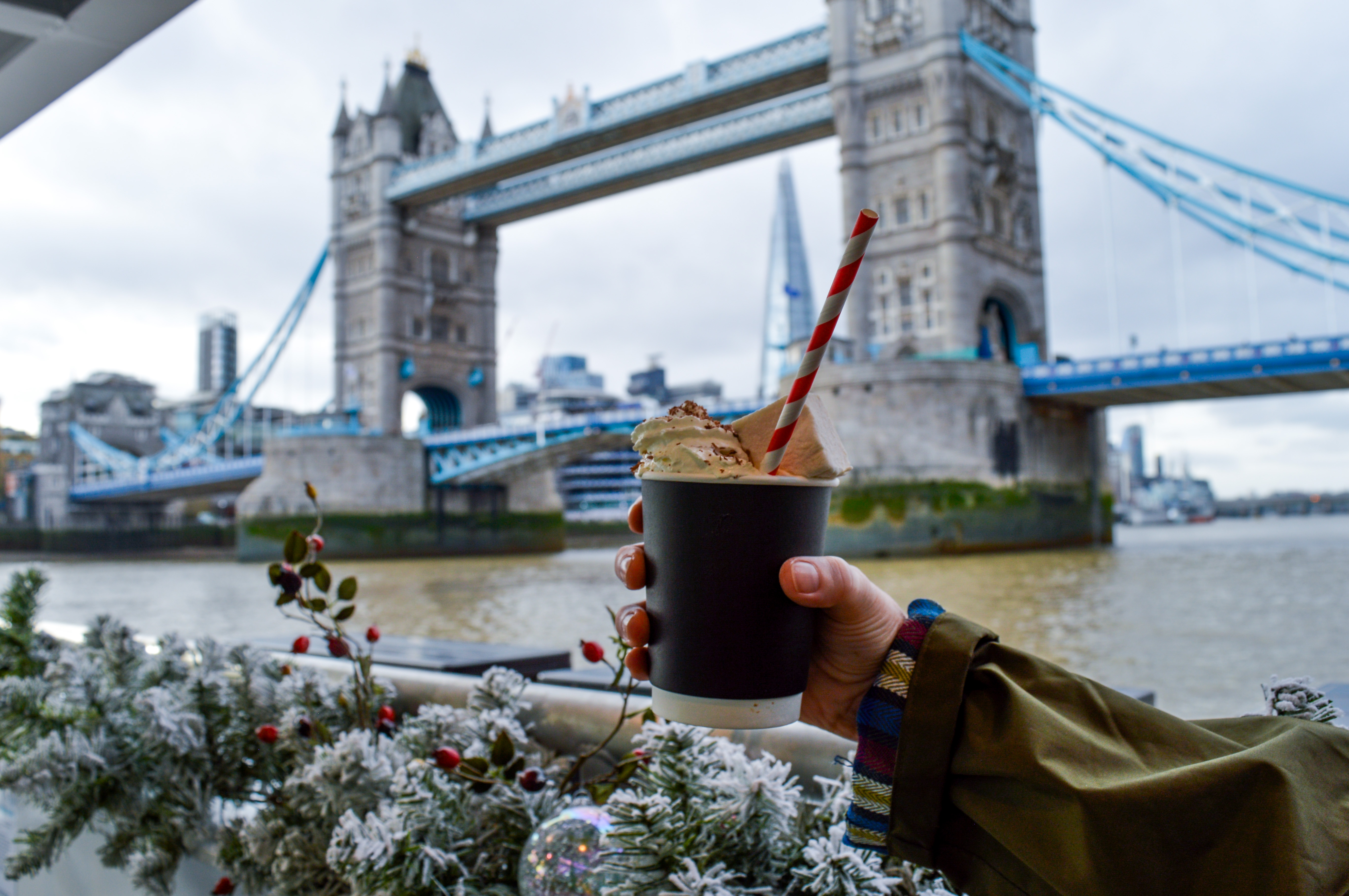 A luxurious hot chocolate aboard the Tower of London River Tour on the River Thames, with Tower Bridge and the Shard in the background